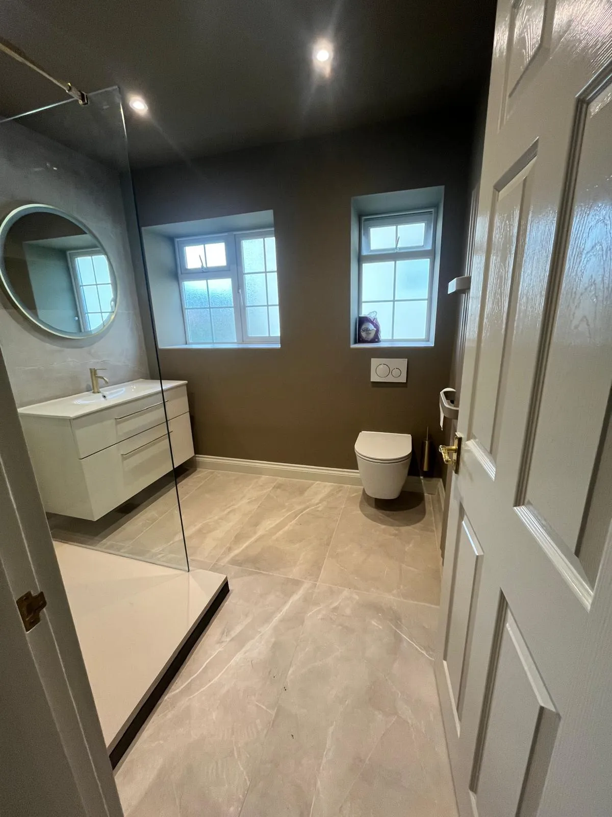 Refurbished shower room with a vanity unit, wall-hung WC and two windows