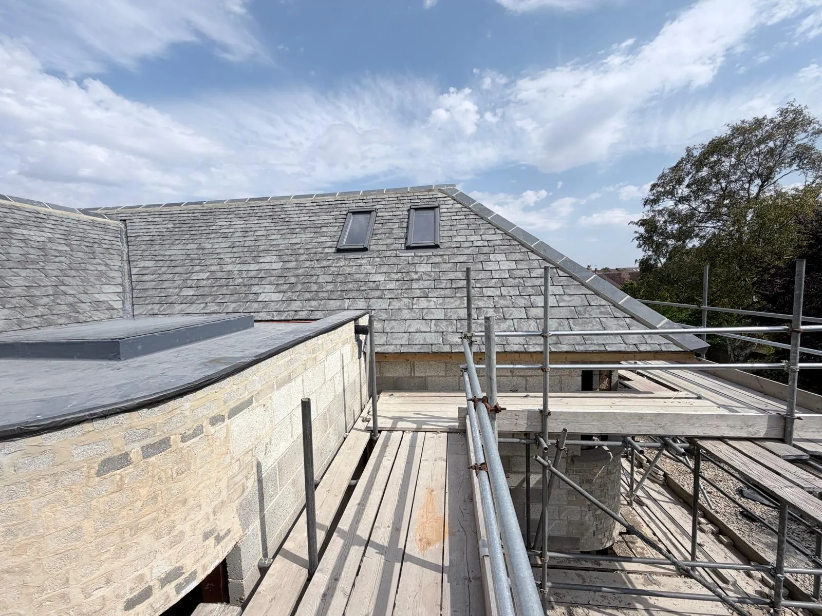 Curved bay with a new flat roof and rooflight beside the finished slate roof