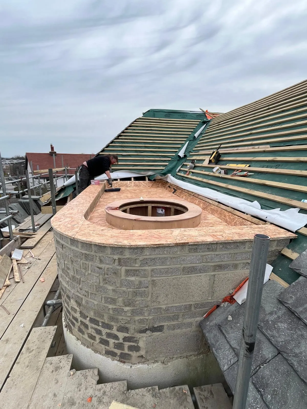Curved blockwork bay under construction with a timber roof deck
