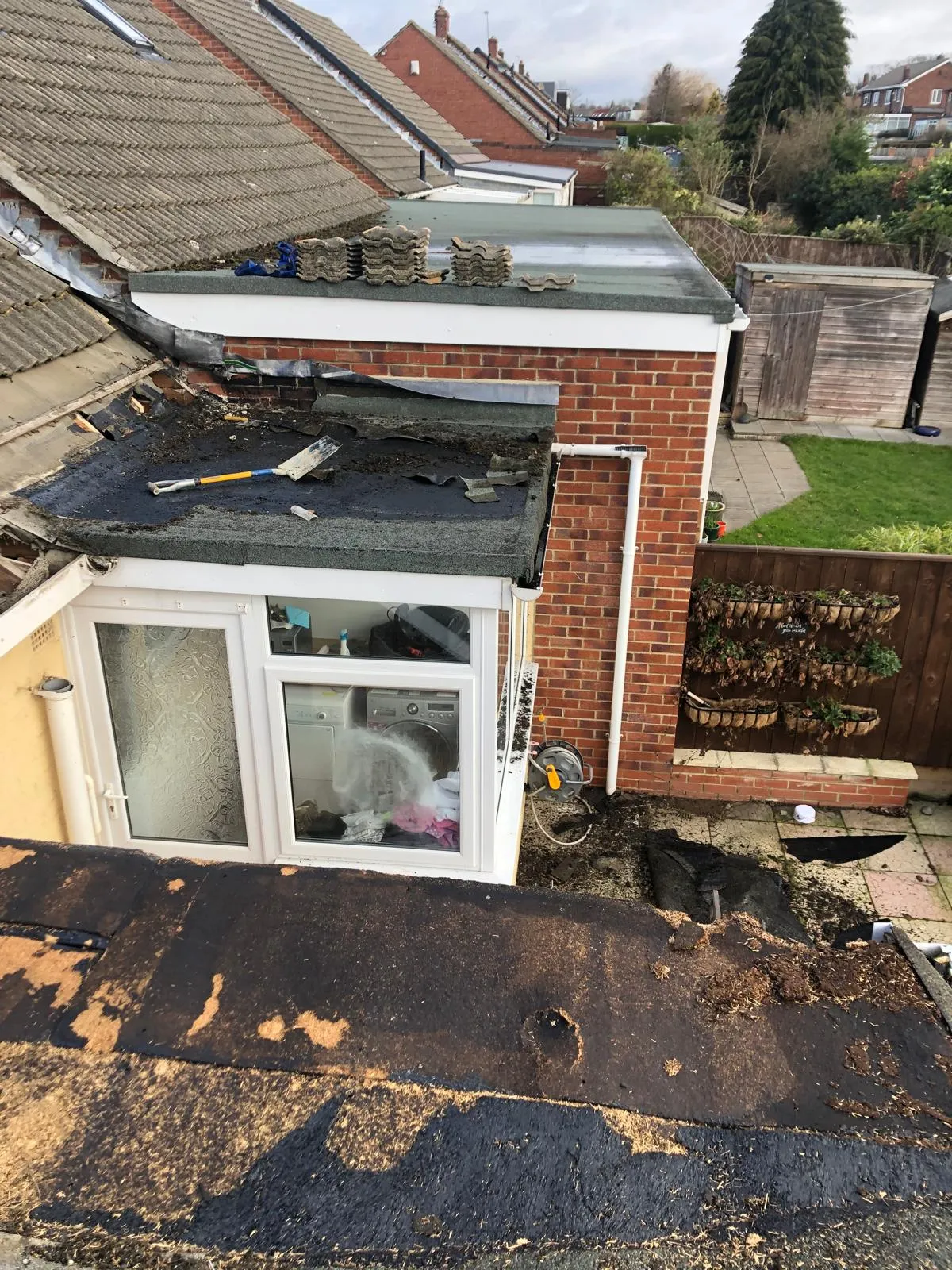 Old flat roof covering being stripped from a rear extension