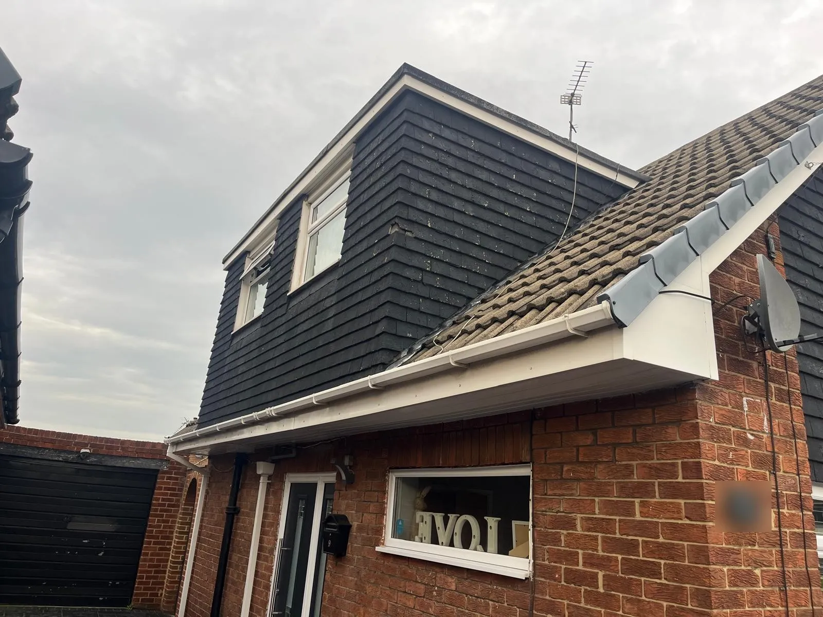 Brick gable end and garage with dark tile hanging above, before rendering