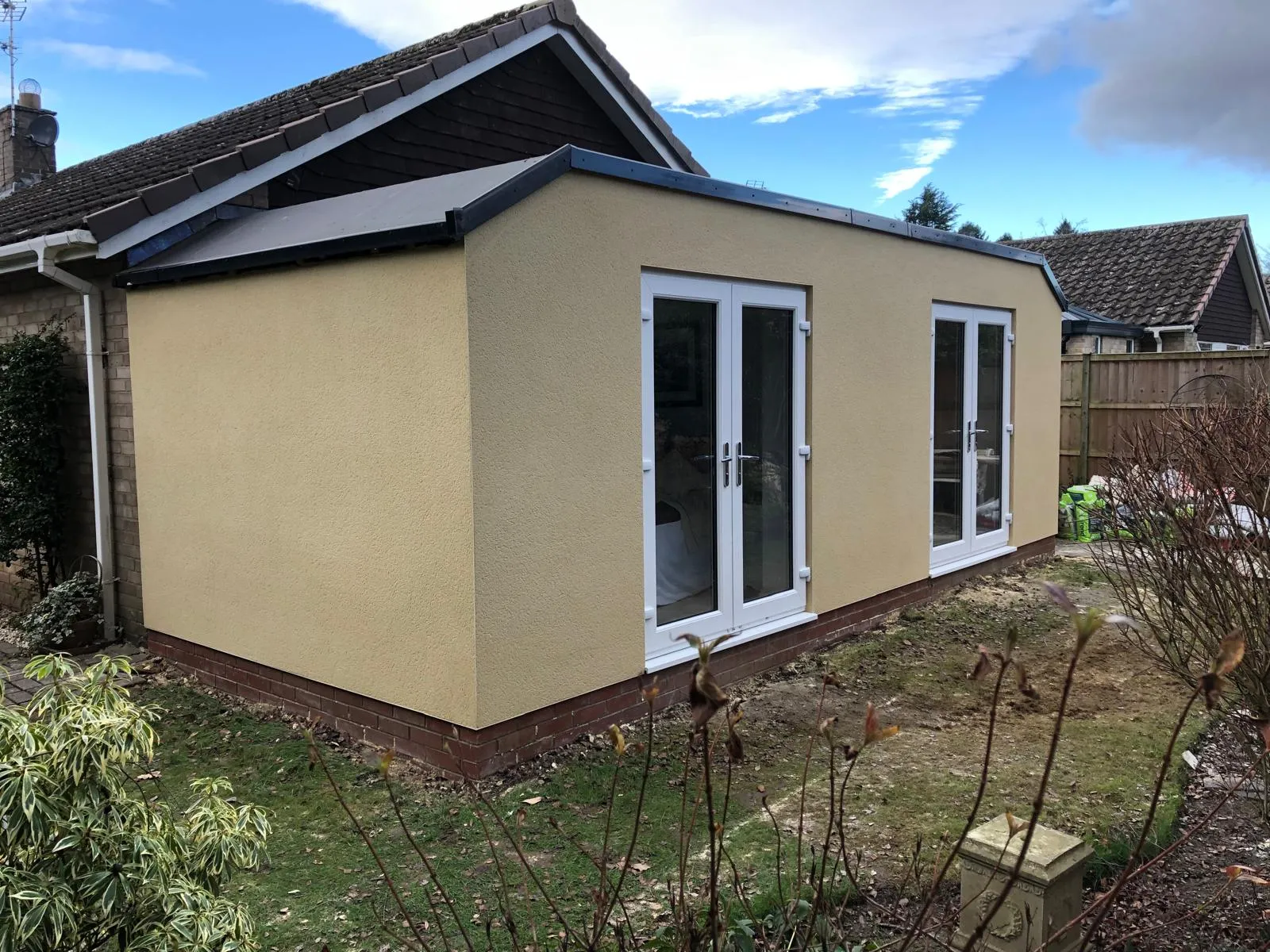 Single-storey extension finished in a textured cream render
