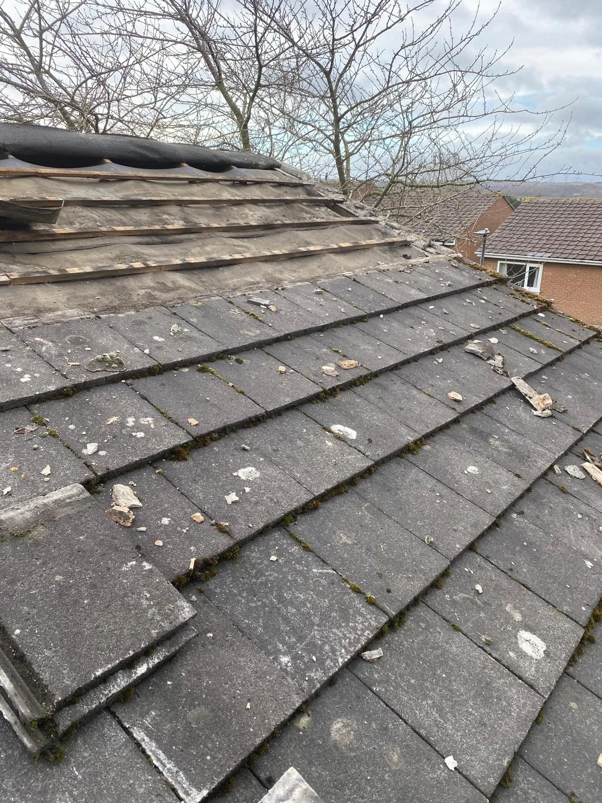 Weathered, moss-covered roof tiles before replacement